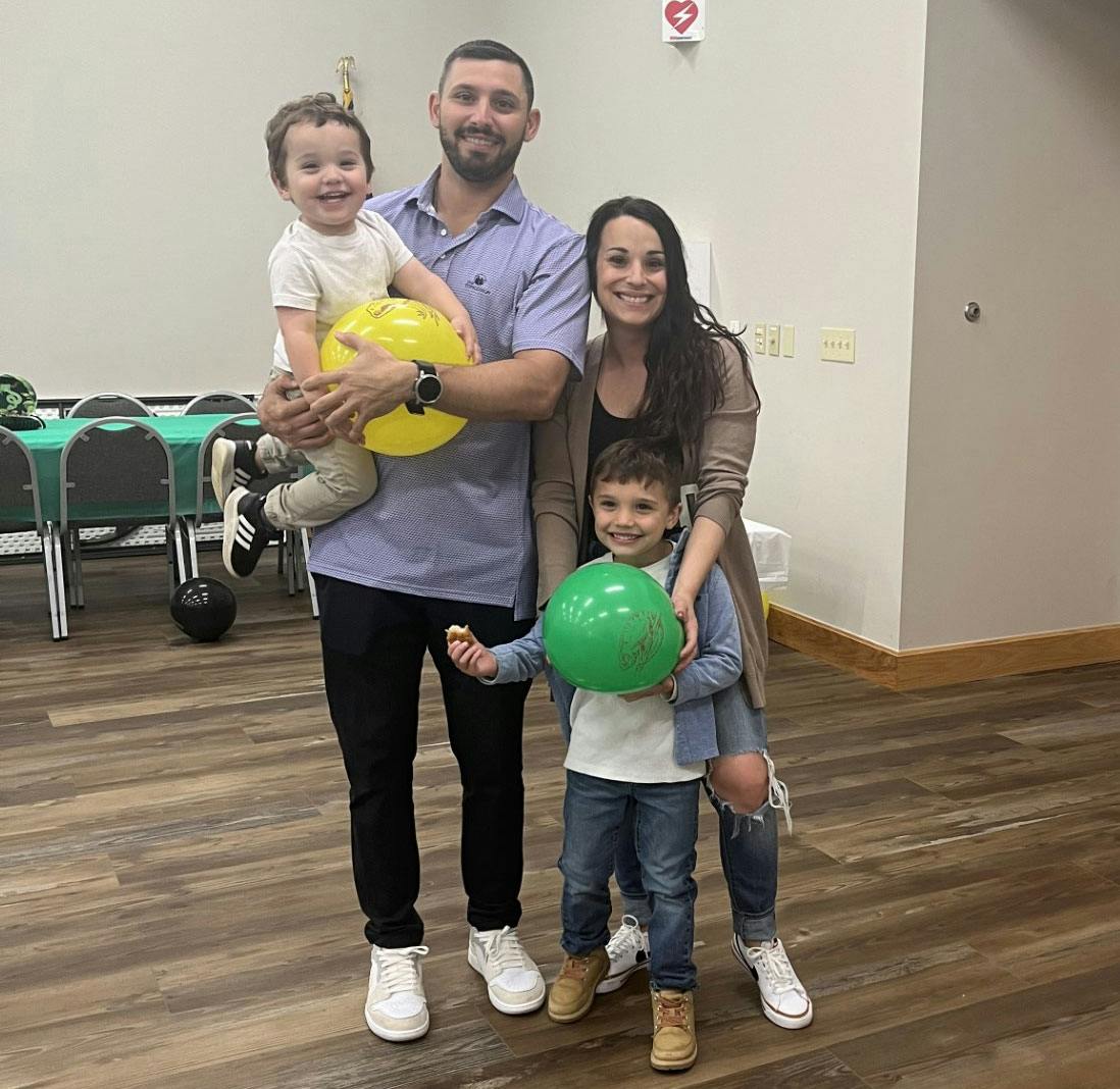 A man, woman, and two young sons. The young ones are holding balloons.