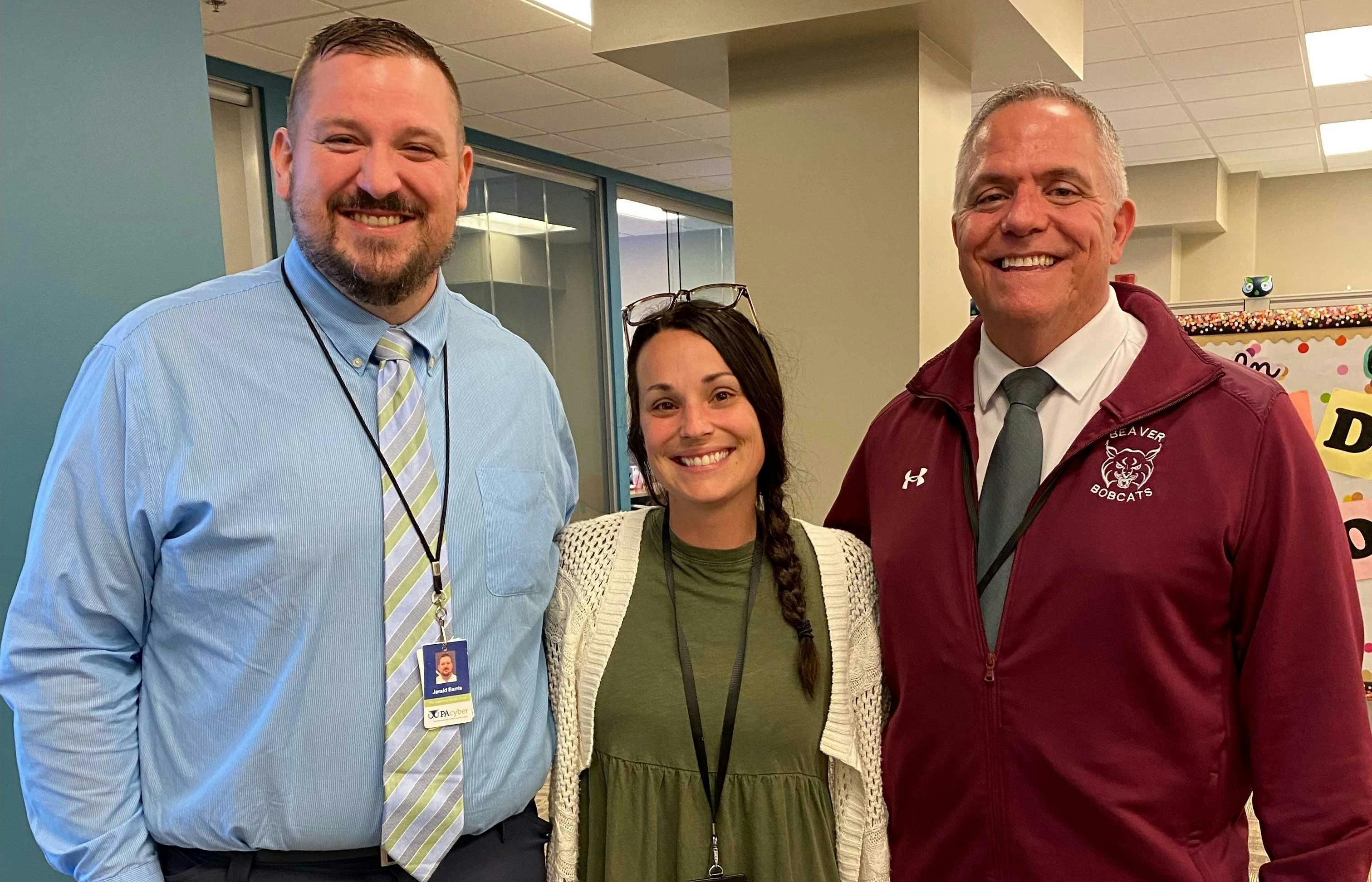 Three adults stand together, two men and a woman.